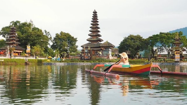 Beautiful girl kayaking on the catamaran at the ulun datu pura bratan temple, in Bali.