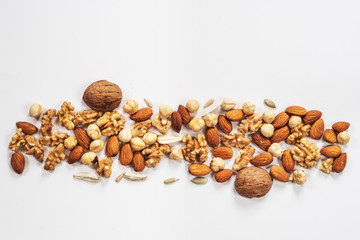 Wooden bowl with mixed nuts on white table top view. Healthy food and snack. Walnut, pistachios, almonds, hazelnuts