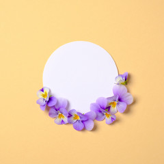 Creative flat lay composition: circle blank paper and blooming flower petals on yellow background. Top view, floral round frame, abstract design. Invitation, greeting card or element for your design