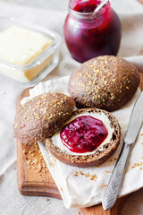 Homemade rye buns with linseeds, sesame and white poppy seeds served with butter and Jostaberry jam