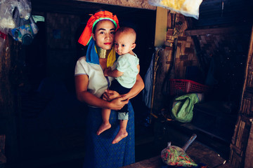 Long Neck Woman is sitting with her child. Tribal village Northern Thailand.