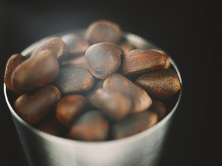 Pine nuts in a cup on black background