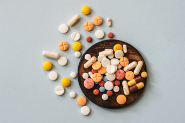 Assorted pharmaceutical medicine pills, tablets and capsules on wooden bowl