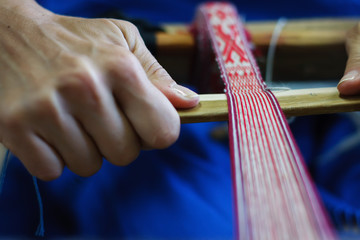 girl's hands weave a traditional belt with Altai ornament on an old loom close-up