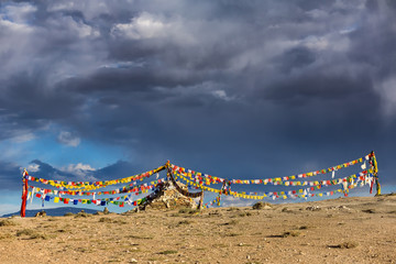 Old stone stupa with tibetan buddhist prayer flags in Ladakh, India.