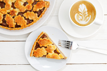 Homemade pie with cottage cheese and prunes and cup of coffee.