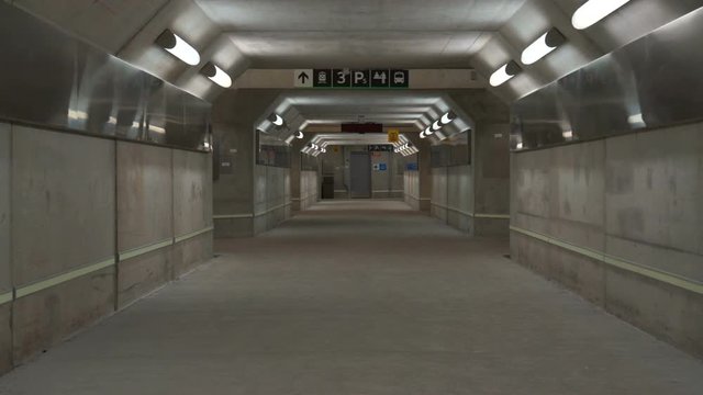 Empty concrete pedestrian tunnel under a train station. An empty concrete subterranean pedestrian tunnel lines with lights and reflective metal It is under a GO train station in Canada