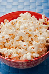 popped popcorn in a bowl over blue background