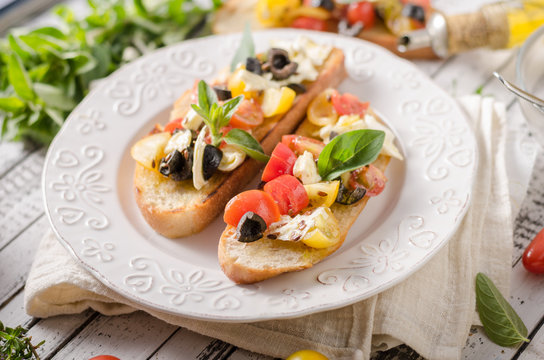 Crostini with tomatoes and olives on beautiful plate