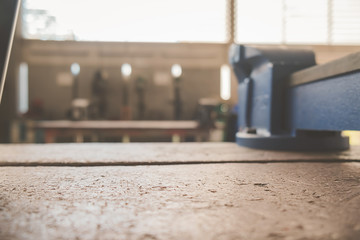 Equipment on wooden desk with man working in workshop background.