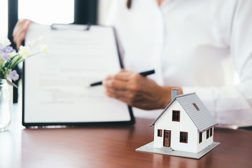 House model with real estate agent and customer discussing for contract to buy house, insurance or...