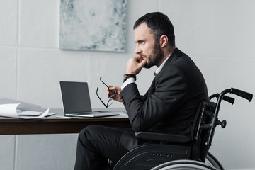 disappointed disabled businessman sitting in wheelchair at workplace