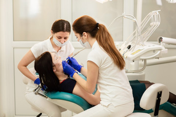 Doctor whit assistant treating teeth of patient, preventing caries. Stomatology concept