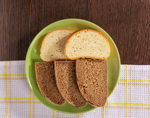 Pieces of wheat and rye bread lie on a plate on the table.