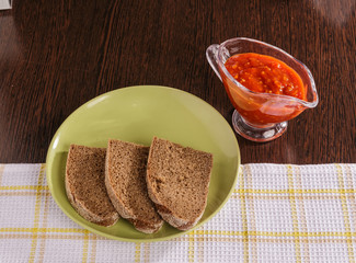 Pieces of rye bread and thick tomato sauce on a plate on the table.