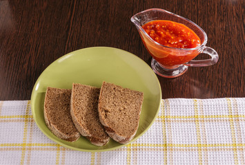 Pieces of rye bread and thick tomato sauce on a plate on the table.