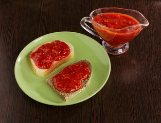 Pieces of rye bread and thick tomato sauce on a plate on the table.