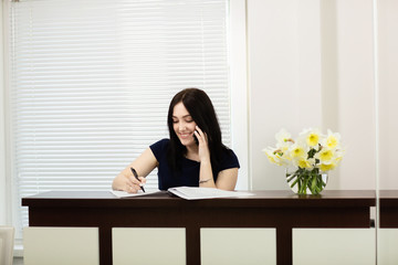 Beautiful girl at the reception desk answering the call in dental office