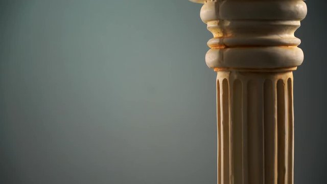Single ancient greek column rotating slowly on blue color background, copy space text area