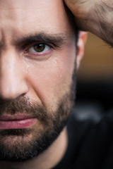 partial view of crying man with tears on face looking at camera