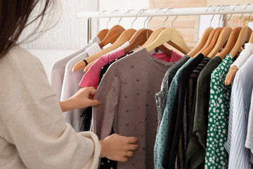 Woman choosing clothes from wardrobe rack, closeup