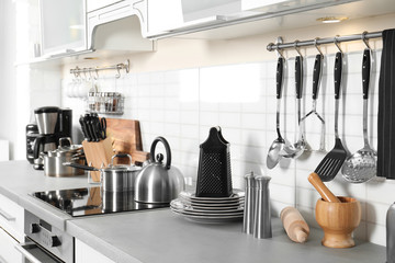 Different appliances, clean dishes and utensils on kitchen counter - obrazy, fototapety, plakaty
