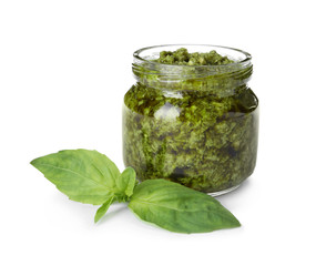 Jar of tasty pesto sauce and basil leaves isolated on white