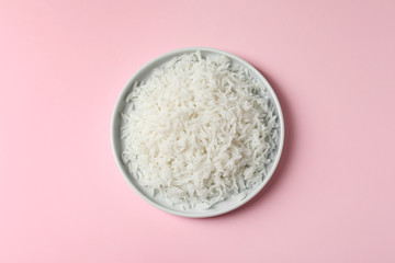 Plate of tasty cooked rice on color background, top view