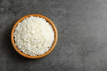 Bowl of tasty cooked rice on grey background, top view. Space for text