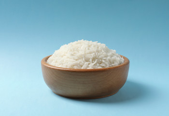 Bowl of tasty cooked rice on color background