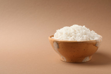 Bowl of tasty cooked rice on color background. Space for text