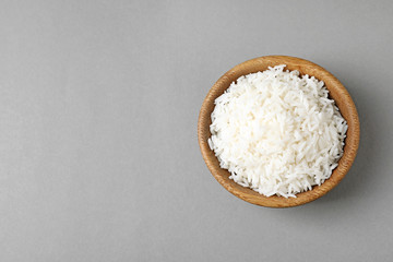 Bowl of tasty cooked rice on grey background, top view. Space for text