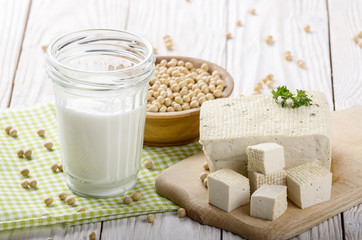 Non-dairy alternatives Soy milk or yogurt in mason jar and tofu on white wooden table with soybeans in bowl aside