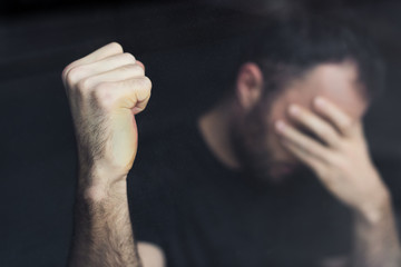 selective focus of depressed man with hand on face holding hand in fist