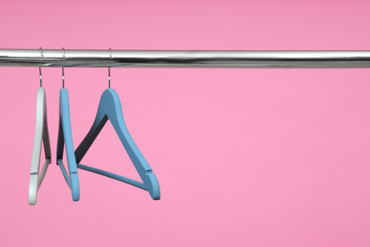 Empty clothes hangers on metal rail against color background. Space for text