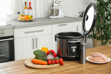 Delicious buckwheat in modern multi cooker and products on wooden table. Space for text