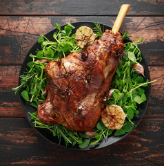 Roast Lamb leg with rosemary and garlic. on black plate, wooden table © grinchh