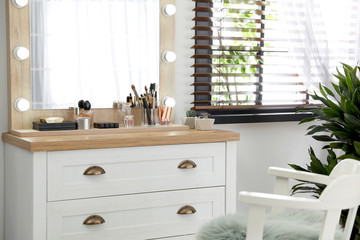 Dressing table with luxury cosmetics and accessories in room near window