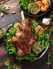 Roast Lamb leg with mint sauce, rosemary and garlic. on black plate, wooden table