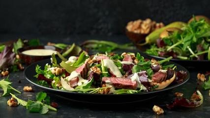 Grilled Beef Steak salad with pears, walnuts and greens vegetables and blue cheese sauce. healthy...