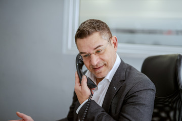 Middle aged businessman in formal wear having a phone talk while sitting in his office. Some people succeed because they are destined to, but most people succeed because they are determined to.