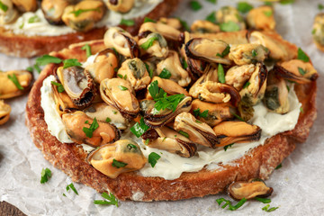 Homemade Mussels on grilled bruschetta, toast with soft cheese and herbs