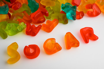Colorful gummy candies on white background with the word SUGAR written with candies