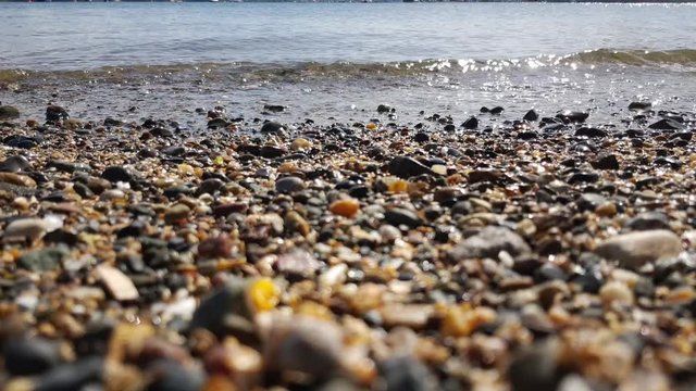 As the gentle crystal clear waves lap the shore over the pebbles and sand.
