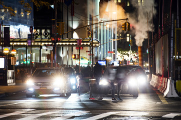 Daily life on the streets of Manhattan with blurred people crossing a busy road intersection at...