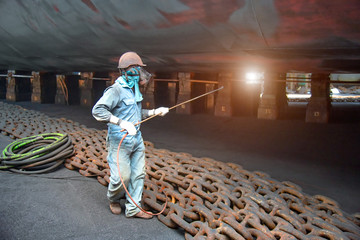 worker, paint man, working for repainting after sand blasting of the bottom layer of the commercial...