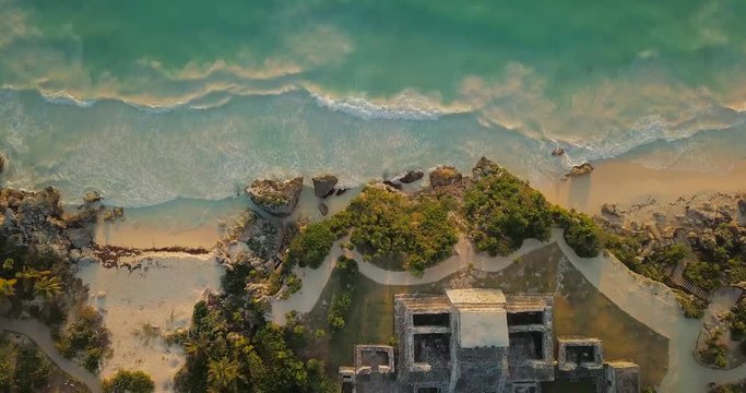 Birds eye and tilt view from Mayan temple Ruin drone sky shot over sea with waves in Tulum Mexico at sunrise