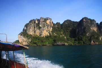 Boat Trip to isolated islands along steep cliffs in blue Andaman Sea near Ao Nang, Krabi, Thailand