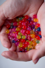 The child is holding multicolored plastic gel balls.