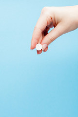 Close-up shot of pill in nurse's hand isolated over blue background. Copy space